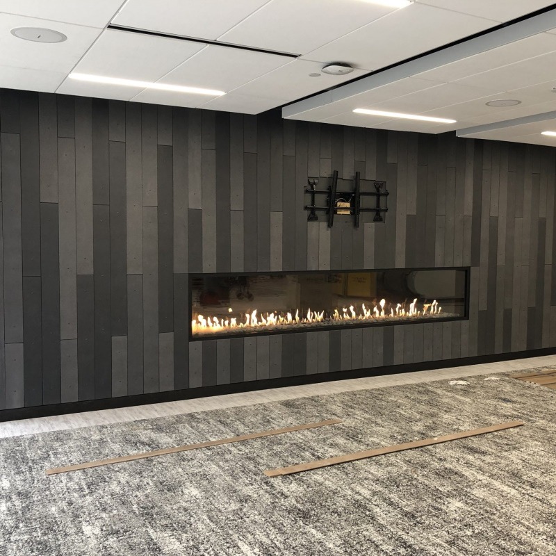 Chimenea lineal de gas empotrada en pared de piedra natural en salón contemporáneo